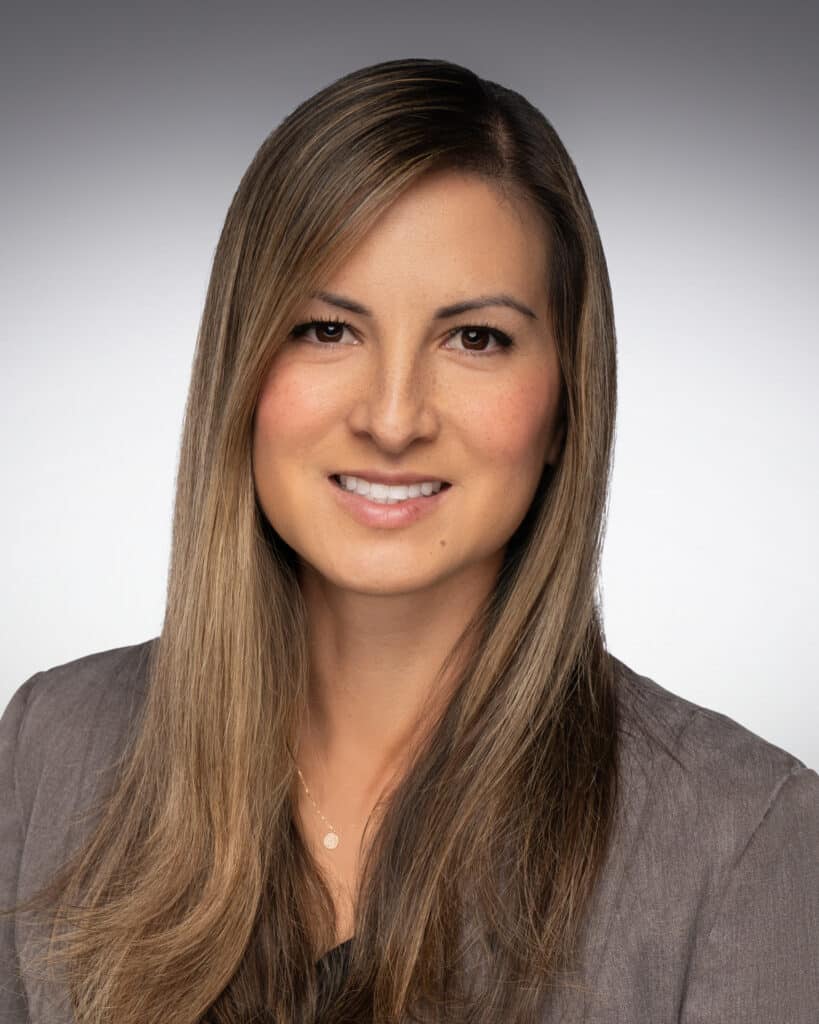 A professional headshot of a director of marketing, featuring a confident individual in business attire, smiling warmly against a neutral background. The image conveys professionalism, approachability, and expertise in marketing.