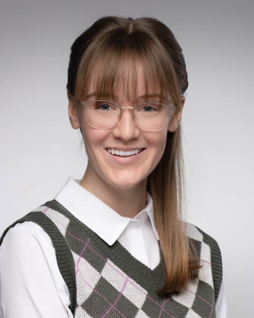 Professional headshot of Emily Kaye, an actor, showcasing a look as an IT nerd with glasses and a focused expression, highlighting their versatility and talent in portraying diverse characters.