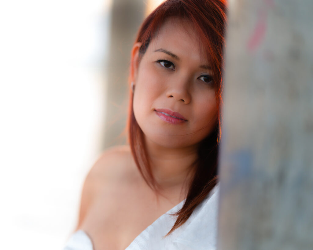 Lifestyle portrait of a woman in white dress outdoors in soft natural light, showcasing authentic emotion and relaxed elegance in a natural setting.