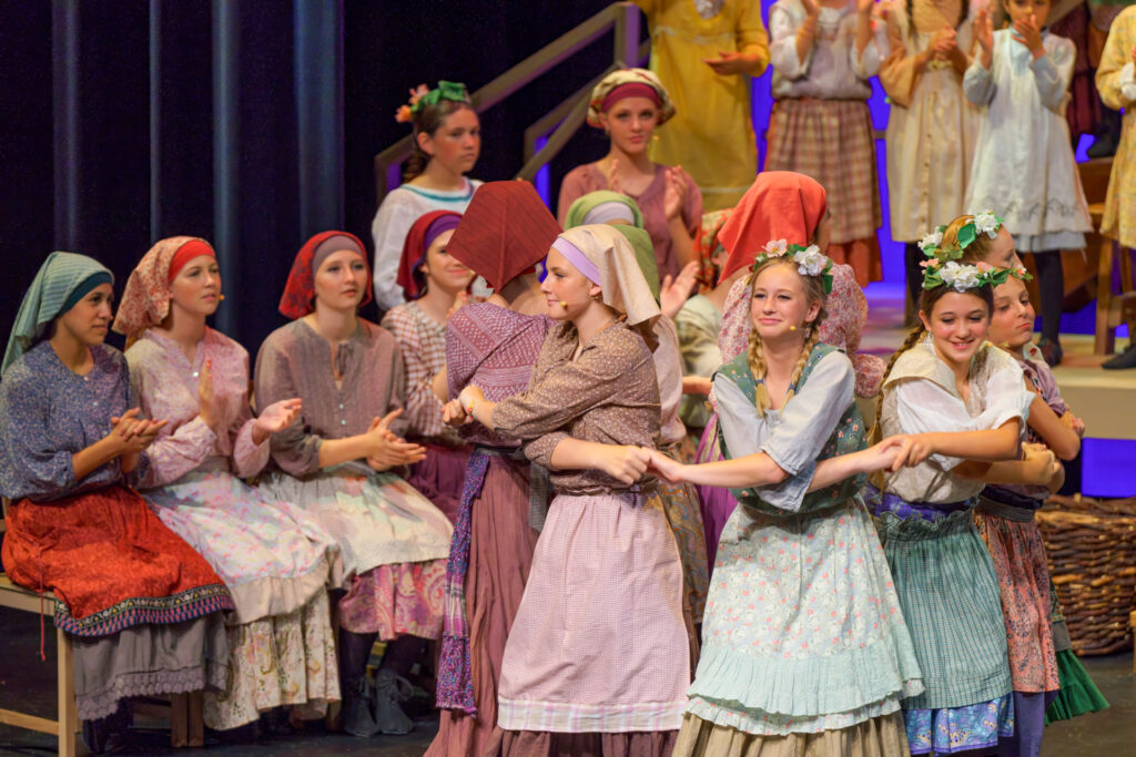 A group of actresses in costumes on stage dancing