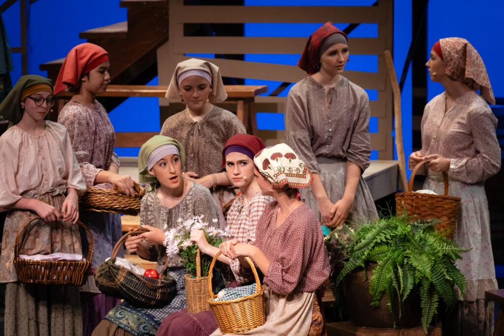 Actors in period costumes with baskets.